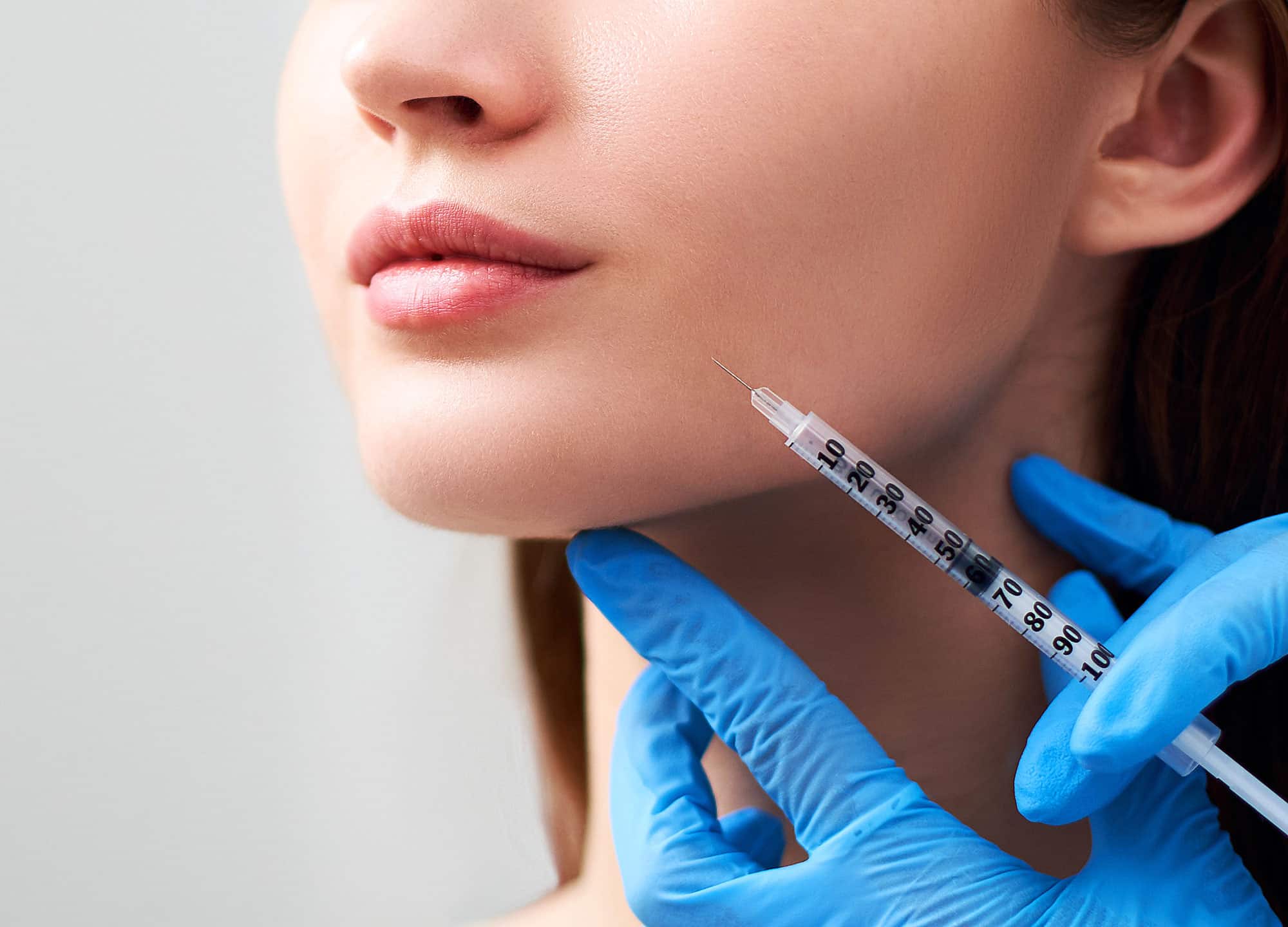 Woman being injected with Radiesse into jawline