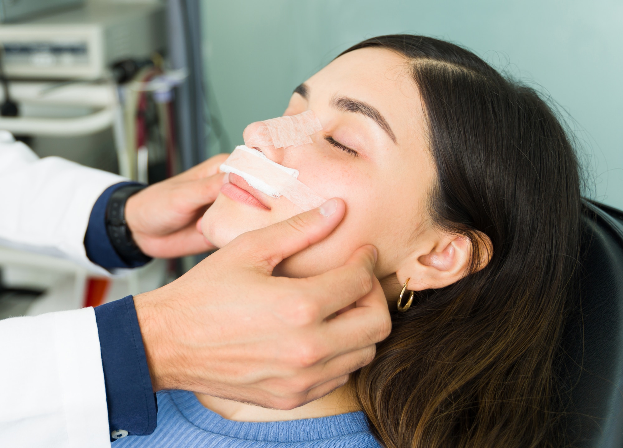 Woman laying down with nose taped after rhinoplasty